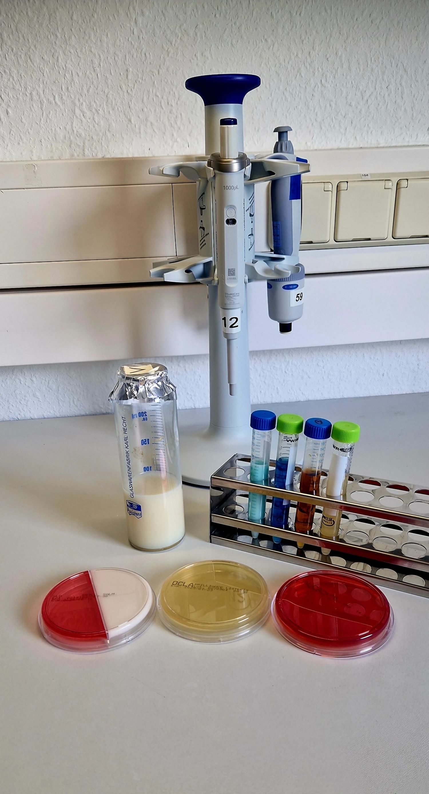 Ein Labor mit einem Mikroskop, einer Vial und einer Flasche auf einem Tisch.